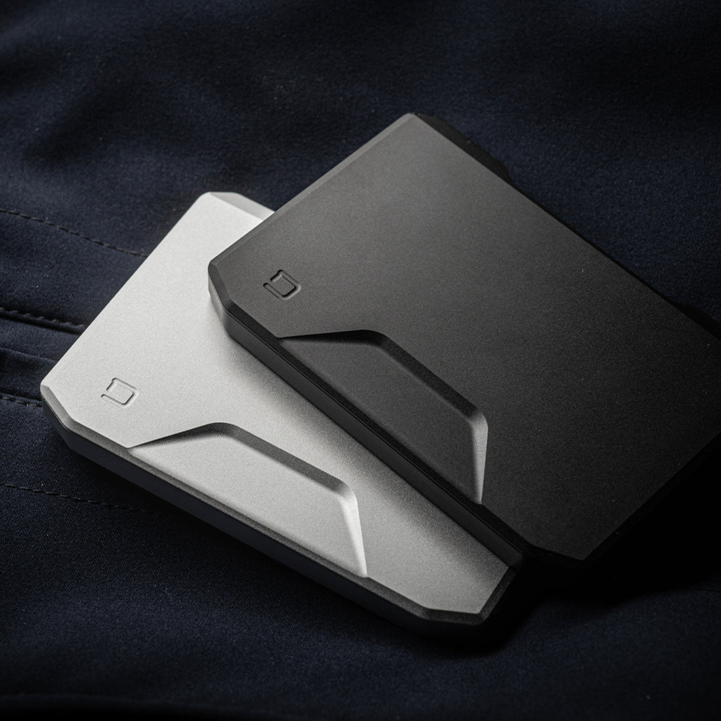 Jet black and satin silver slide kick wallets, stacked on dark fabric