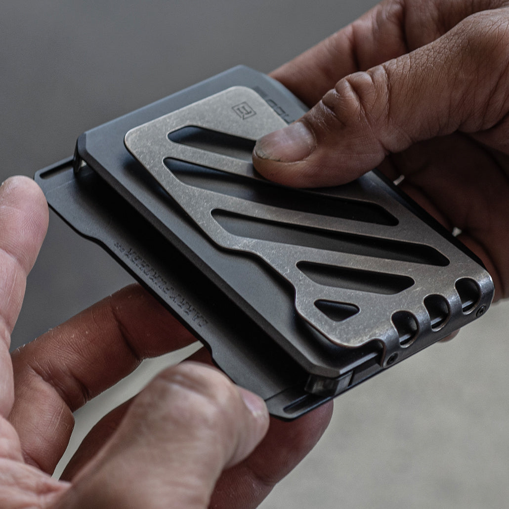 Black slide wallet being adjusted in hands with titanium money clip exposed